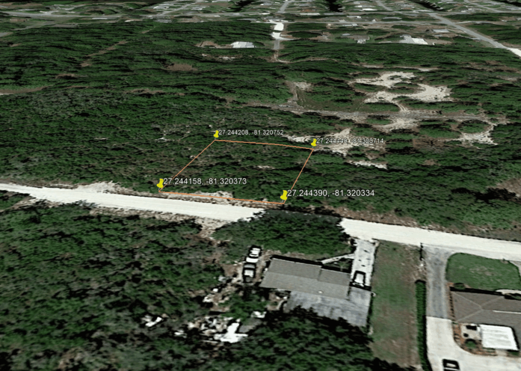 Aerial view of a rectangular parcel outlined in orange with GPS pins, located in green scrubland beside a road and suburban buildings.