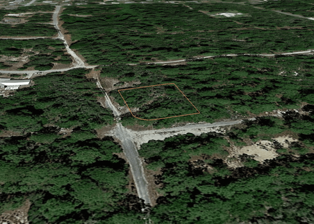 A wooded area with an orange-outlined vacant lot bounded by dirt roads in a rural landscape.