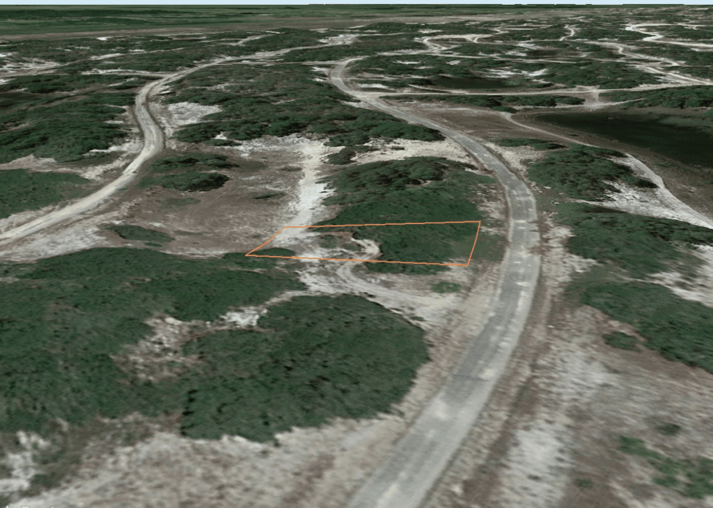 Aerial view of scrubby hills with winding dirt roads and a small rectangular parcel outlined in orange beside a paved road.