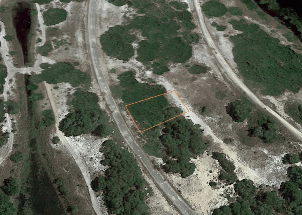 Aerial view of a winding road through a rocky hillside with an orange-outlined rectangular land plot.
