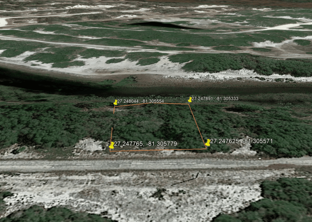 Aerial view of a rectangular land parcel outlined in orange with four GPS corner pins along a dirt road.